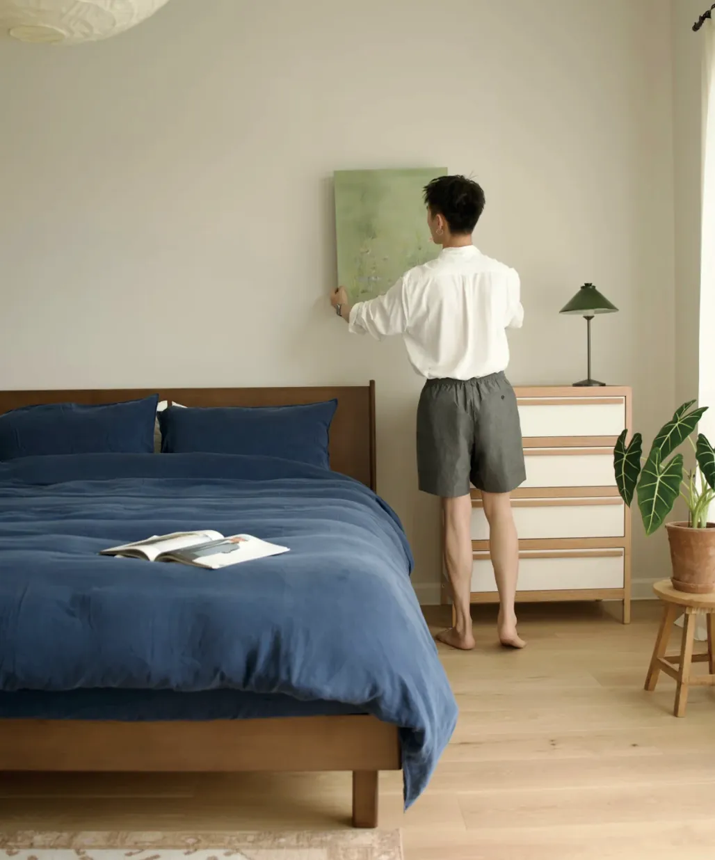A calm bedroom with a navy bedspread and a warm bedside lamp.